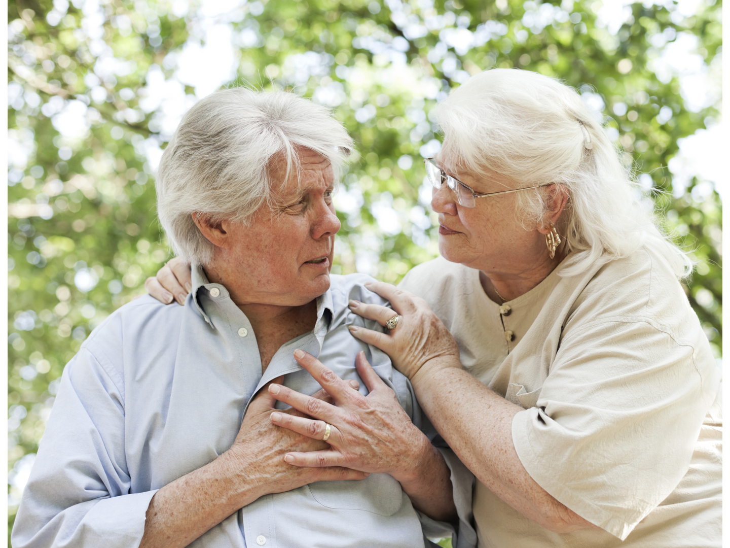 A senior man experiencing chest pain. A senior woman comforts him.